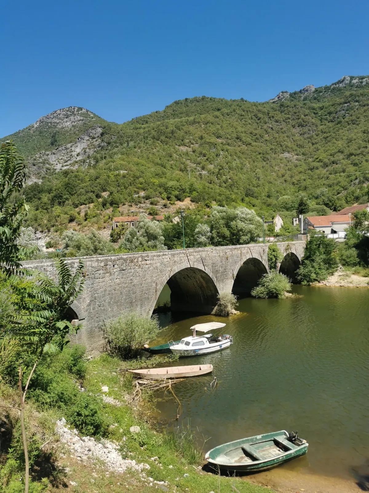 Old stone arched bridge over Rijeka Crnojevića with boats